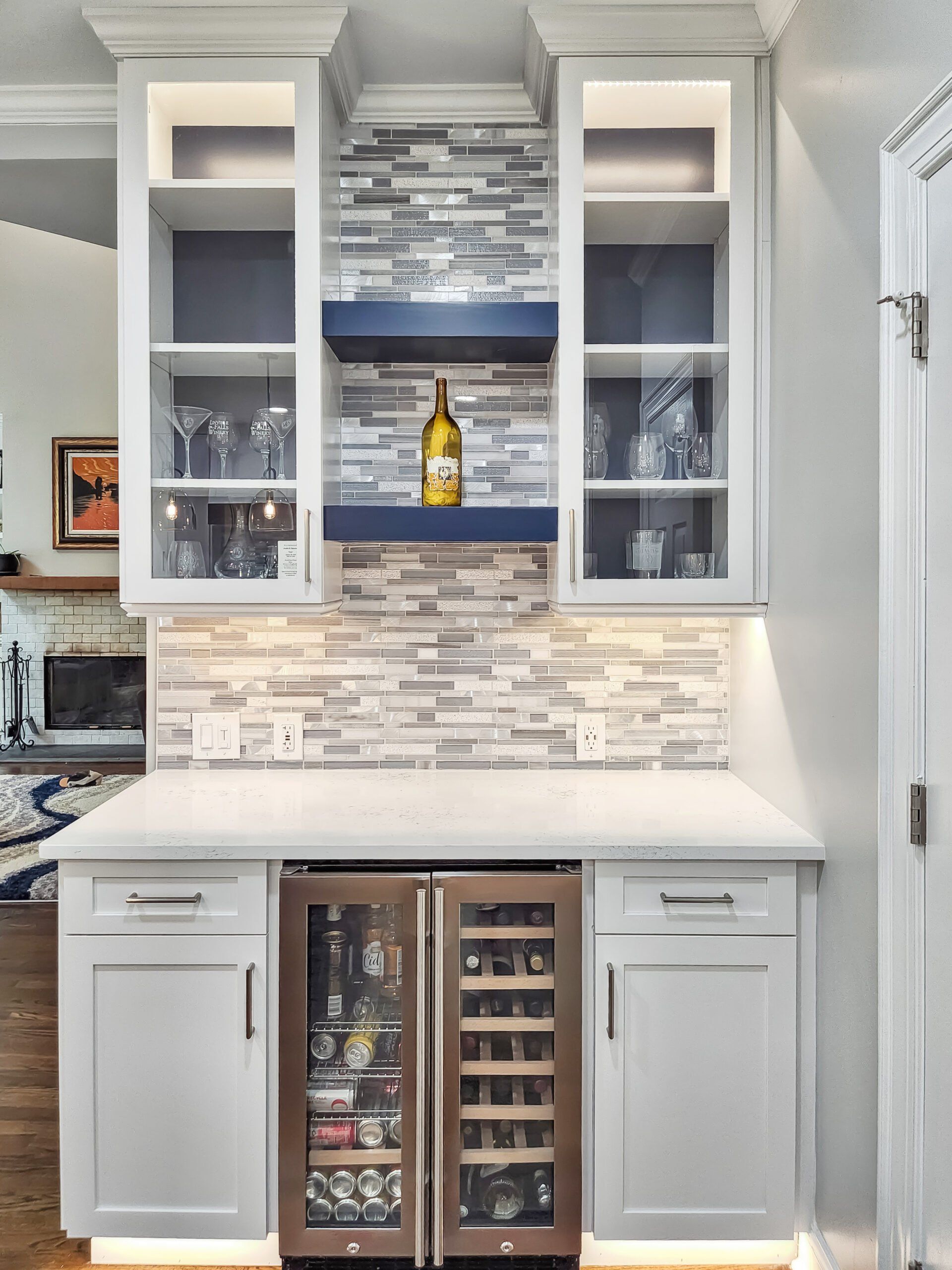A kitchen with a wine cooler and a bottle of wine on a shelf.