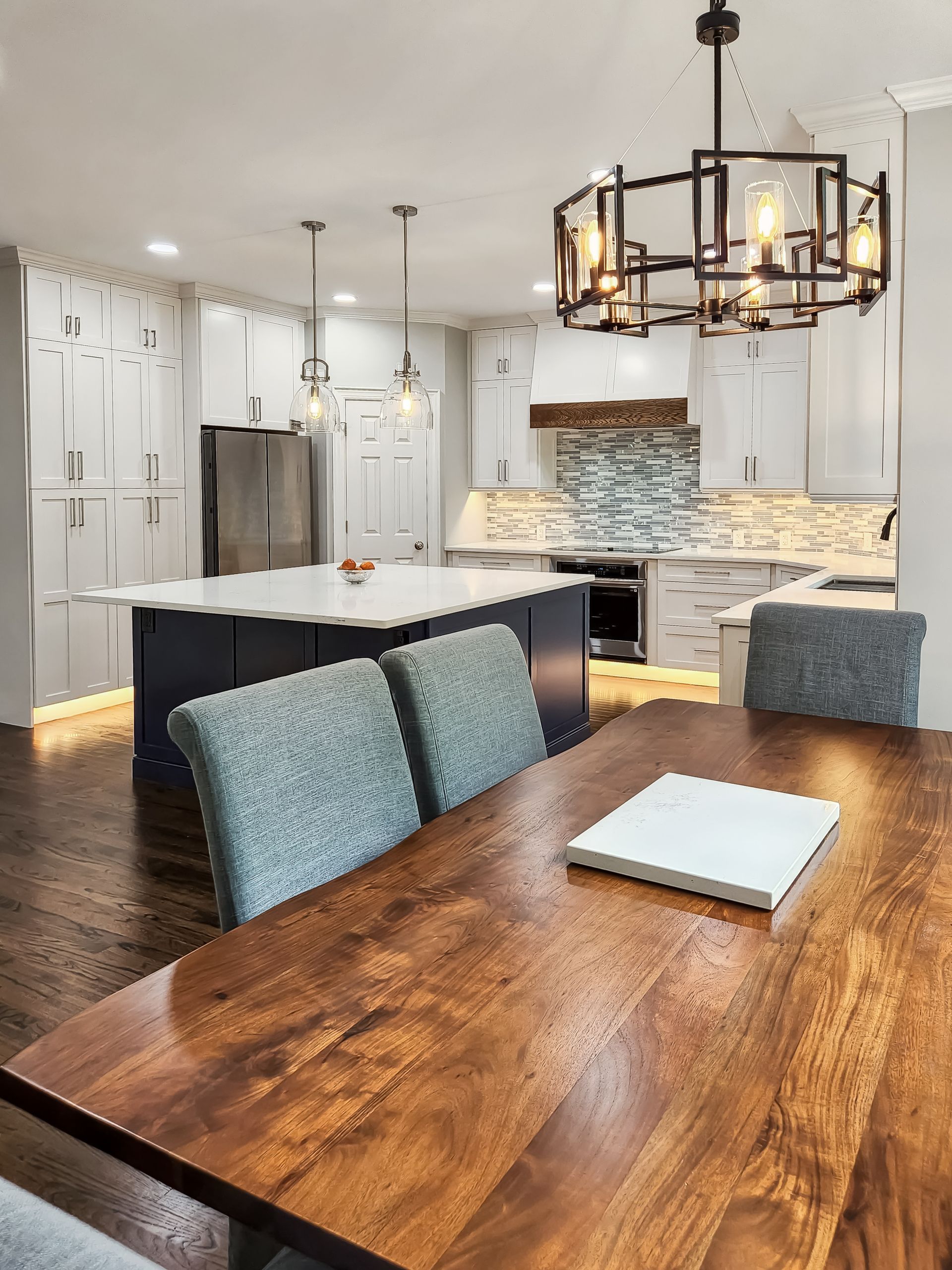 A kitchen with a wooden table and chairs and a chandelier hanging from the ceiling.