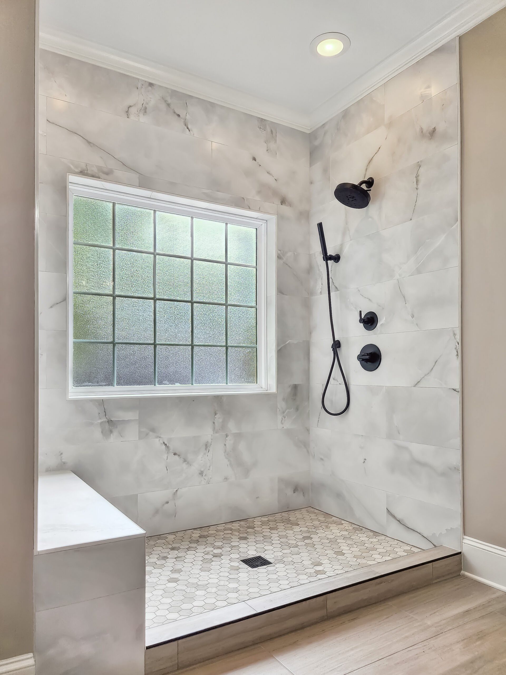 A bathroom with a walk in shower and a window.