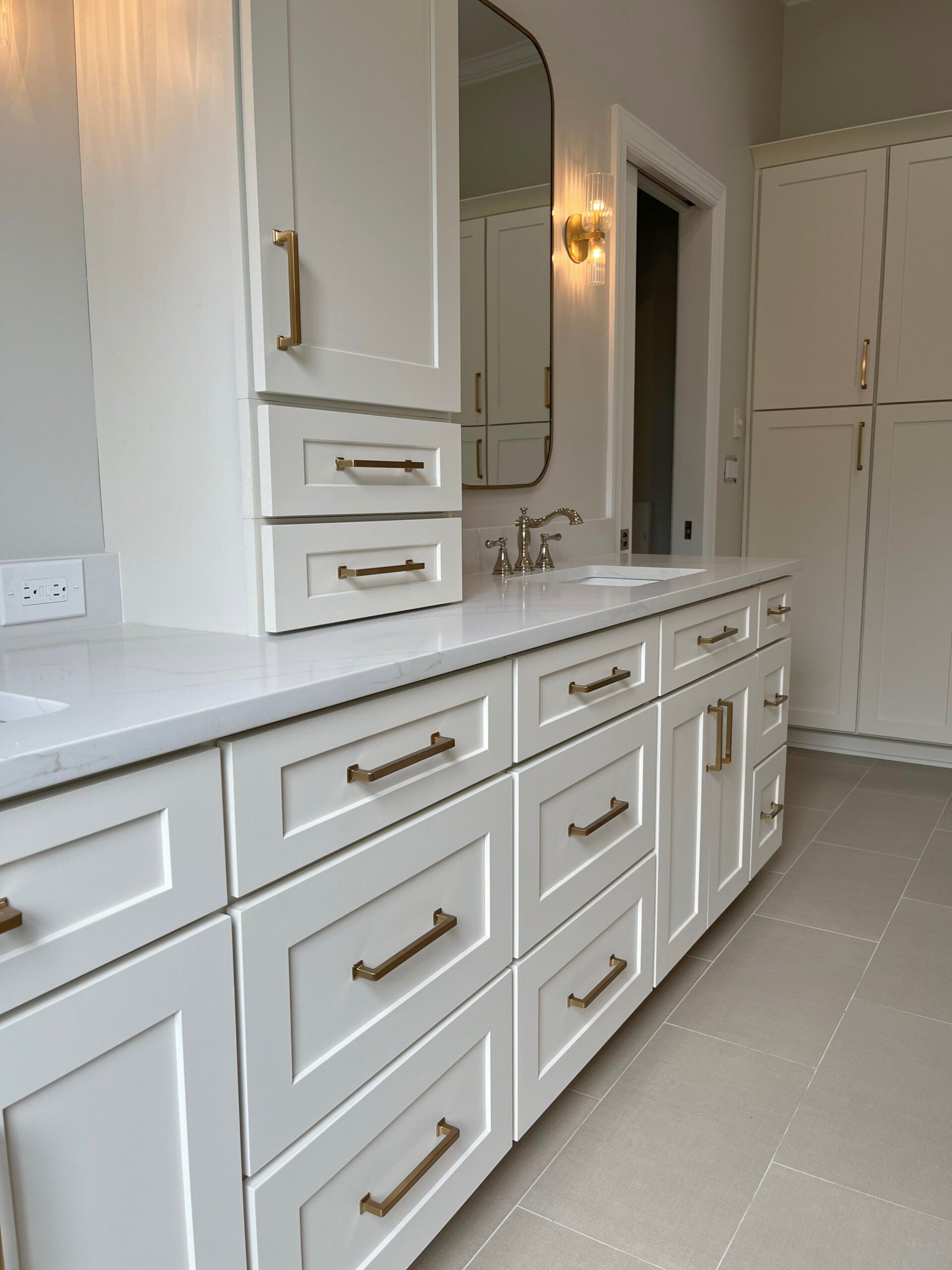 A bathroom with white cabinets, drawers, a sink and a mirror.