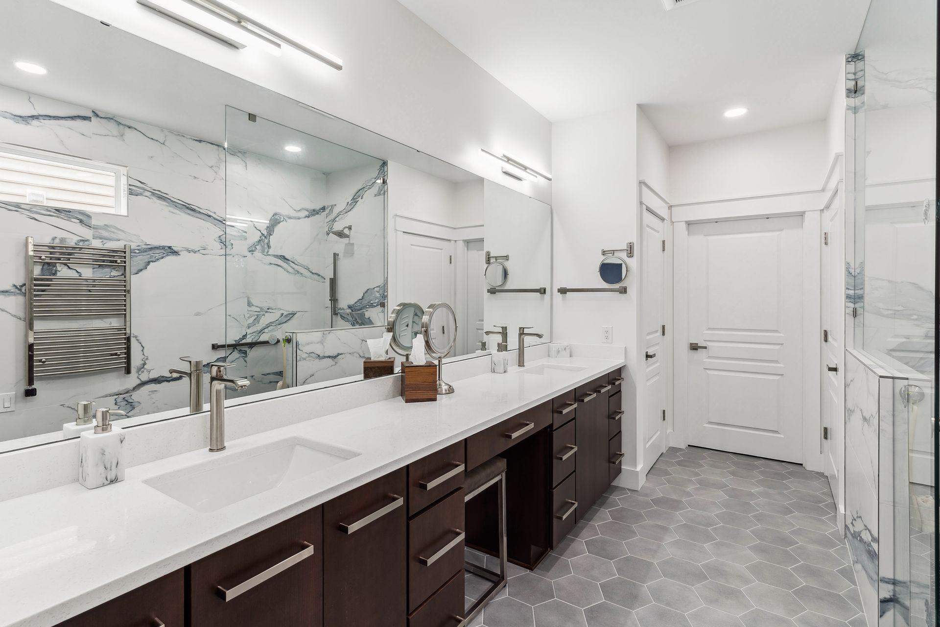 A bathroom with blue cabinets and gold handles and a tiled floor.