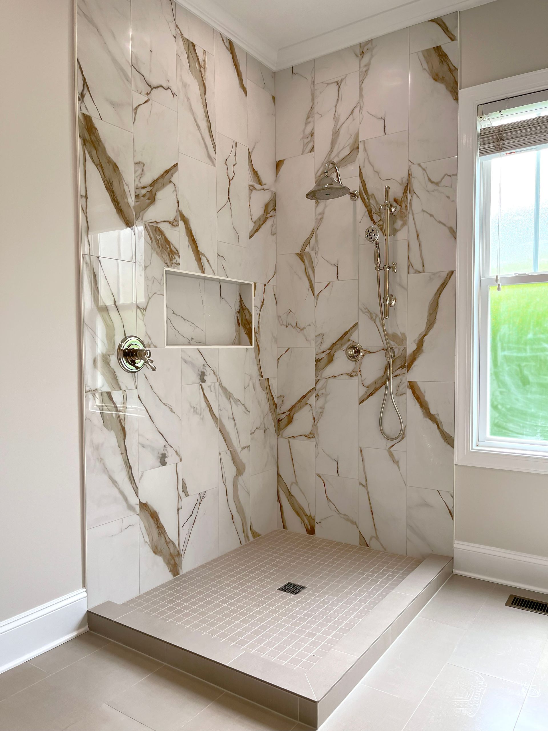 A bathroom with a walk in shower and marble walls.