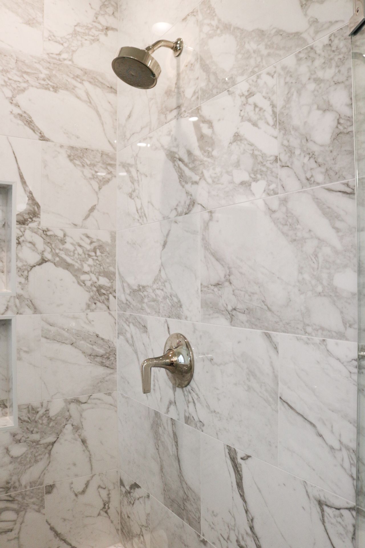 A shower head is hanging from a marble wall in a bathroom.