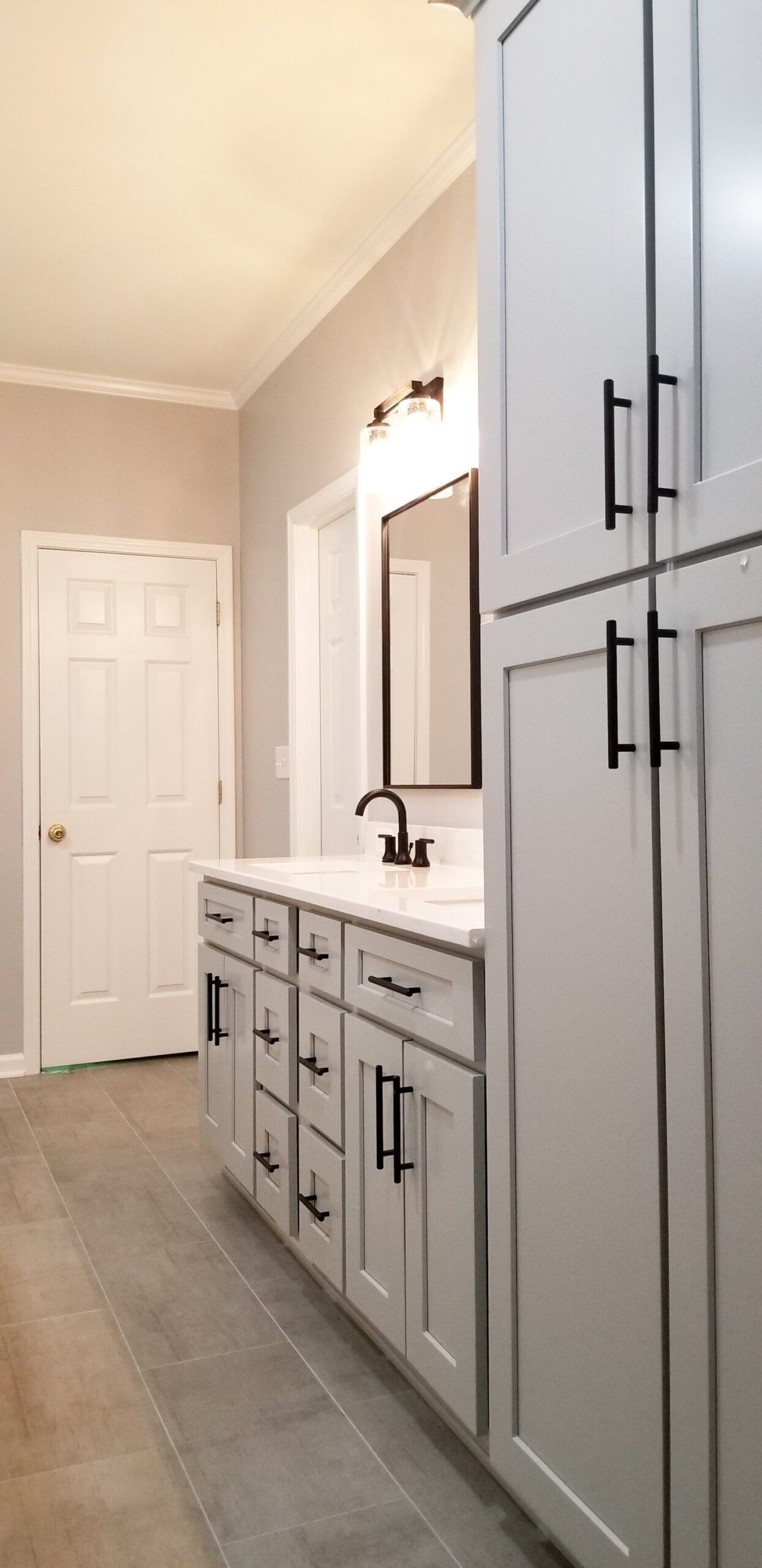 A bathroom with white cabinets, a sink, and a mirror.