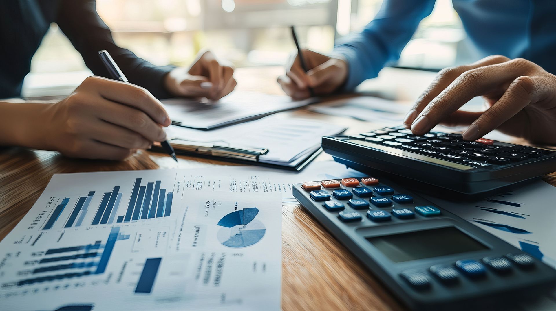 Accounting firm professionals reviewing financial reports with calculator and charts on desk.