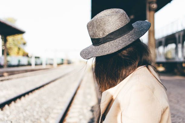 Mysterious woman dressed with a beige trench coat and hat.