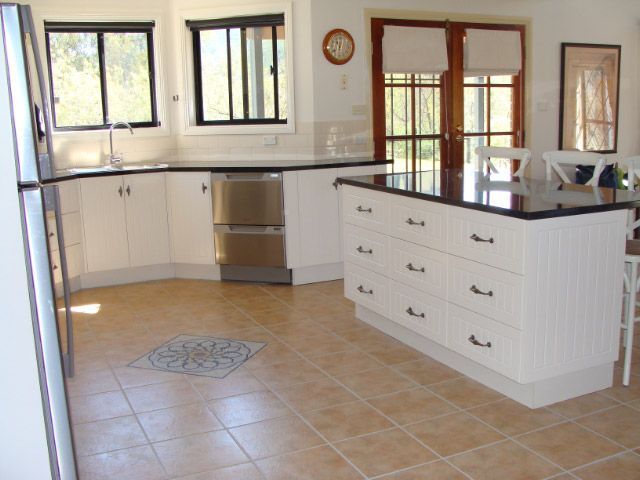 Bright Kitchen with White Cabinets, Black Countertops, Tiled Floor, and Large Windows — Simmonds Kitchens in Quirindi, NSW