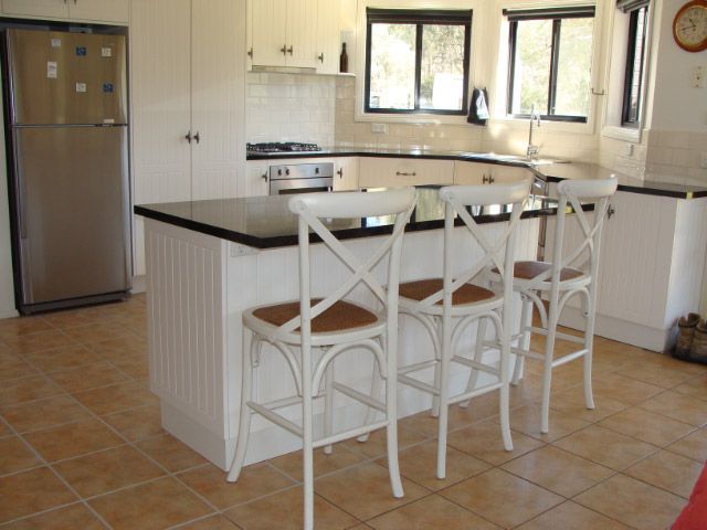 Bright Kitchen with White Cabinets, Tiled Floor, Island Counter, and Three White Chairs — Simmonds Kitchens in Gunnedah, NSW