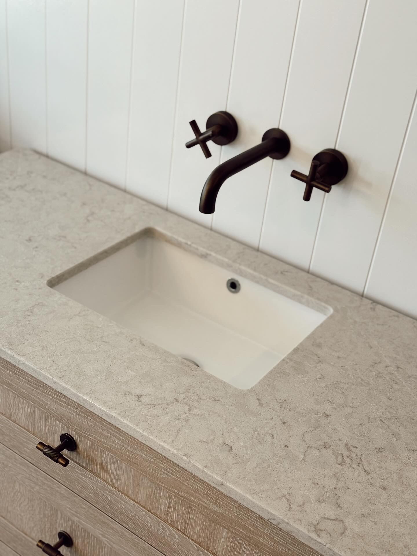 Modern bathroom vanity with white sink, beige countertop, and black wall-mounted faucet