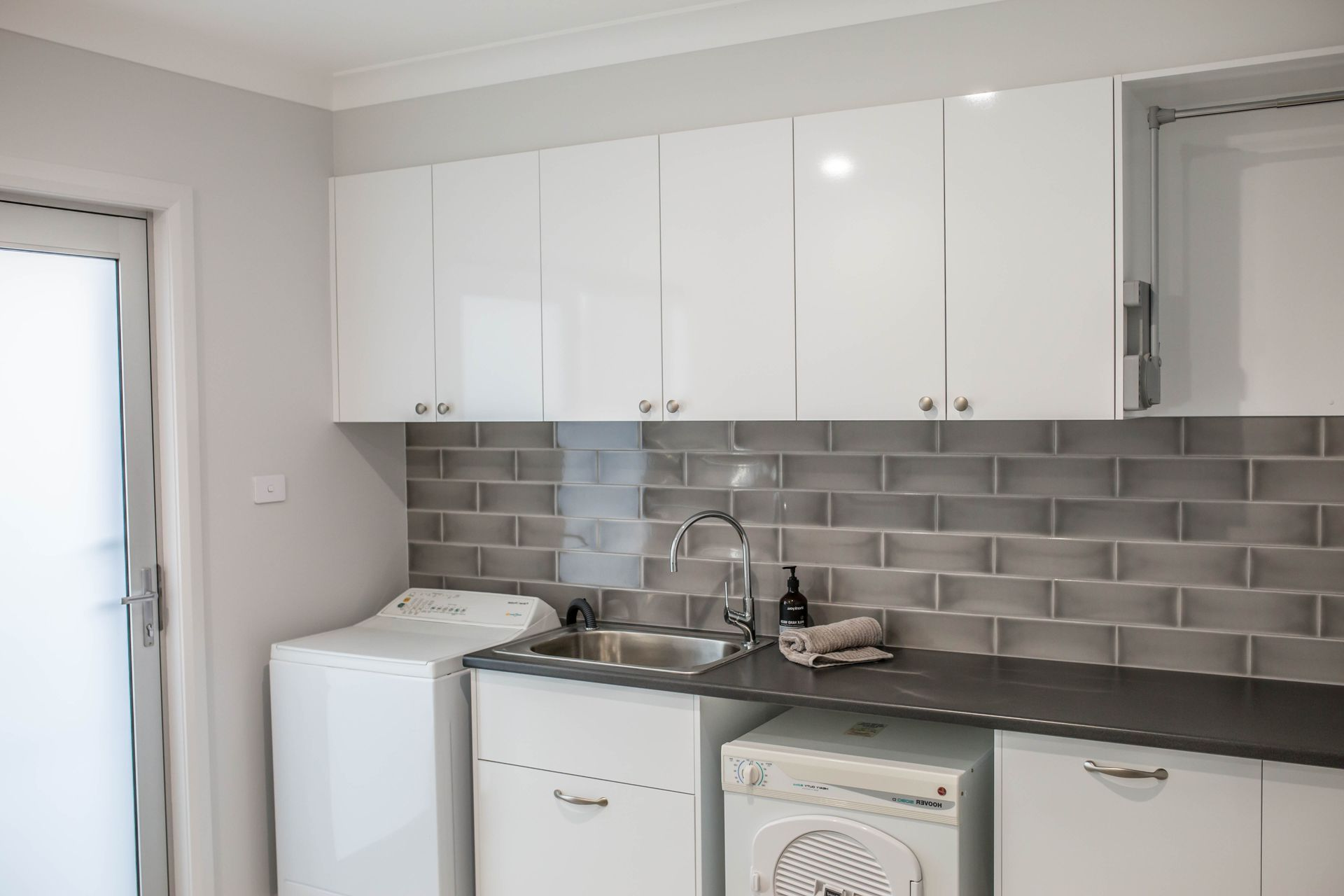 Minimalist White Kitchen with Long Counter, Sink, Cabinets, and Tiled Floor — Simmonds Kitchens in Tamworth, NSW