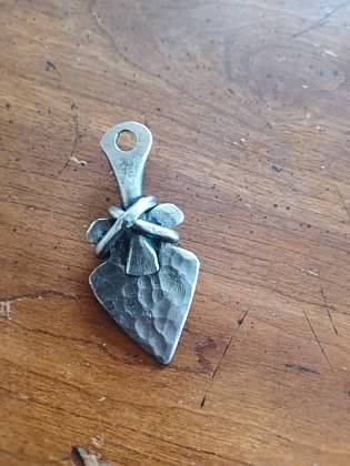 A silver pendant is sitting on top of a wooden table.