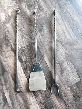 Three metal utensils are sitting on a wooden floor.