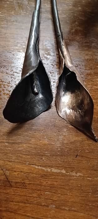 Two metal spoons are sitting on a wooden table.