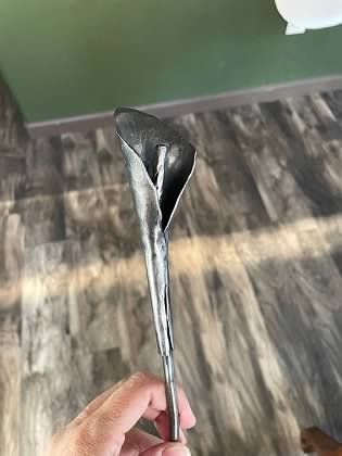 A person is holding a metal flower in their hand.