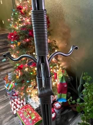 A coat rack is sitting in front of a christmas tree.