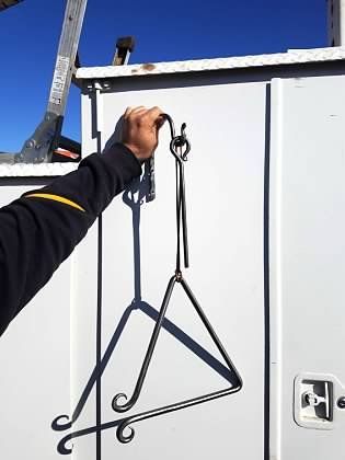 A person is holding a metal object that looks like a triangle.