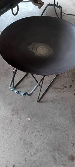 A large black pan is sitting on top of a concrete floor.