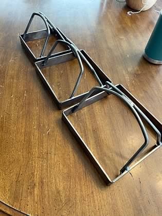 A pair of metal napkins holders sitting on top of a wooden table.