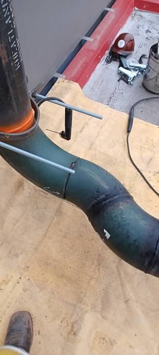 A person is welding a pipe on a wooden table.