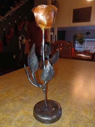 A metal rose sculpture is sitting on a table.