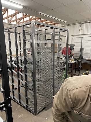 A man is standing in front of a metal cage in a factory.