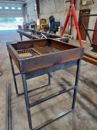 A metal table with a wooden top is sitting in a garage.