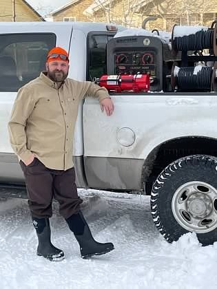 A man is standing next to a truck in the snow.