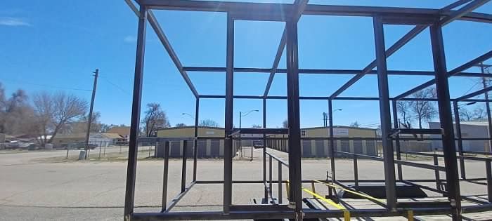 A metal structure is being built in a parking lot.