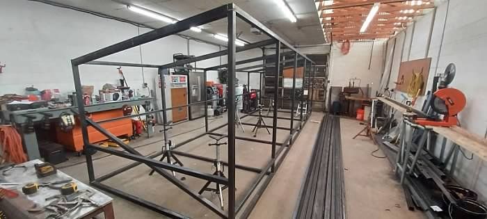 A large metal structure is being built in a factory.