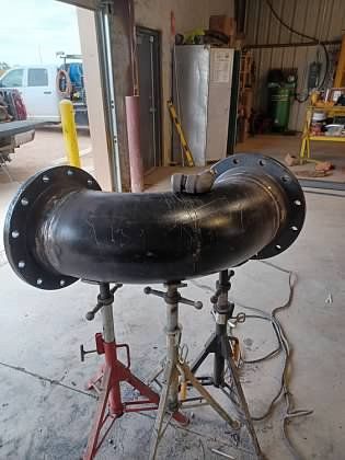 A large pipe is sitting on a stand in a garage.