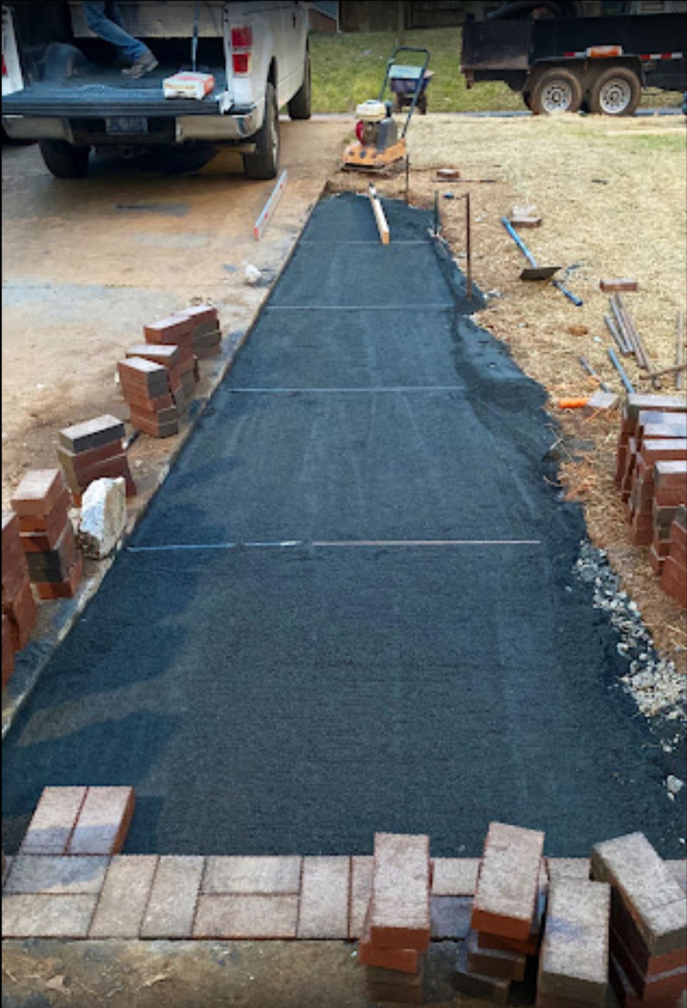 A brick walkway is being built next to a truck