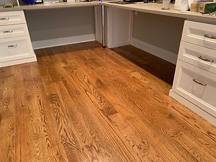 Hardwood floor with desks on either side. Wooden cabinets and a light-colored countertop.