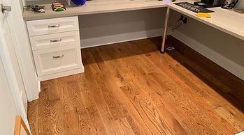 Wooden desk with white cabinets on hardwood floor.