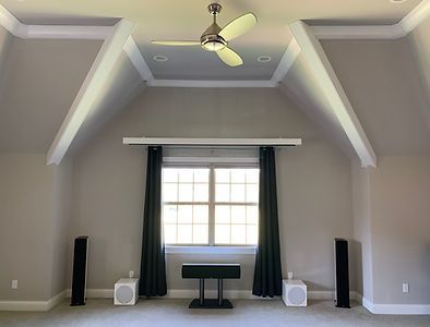Acoustic room with speakers, a window, dark curtains, and a ceiling fan in a gray space.