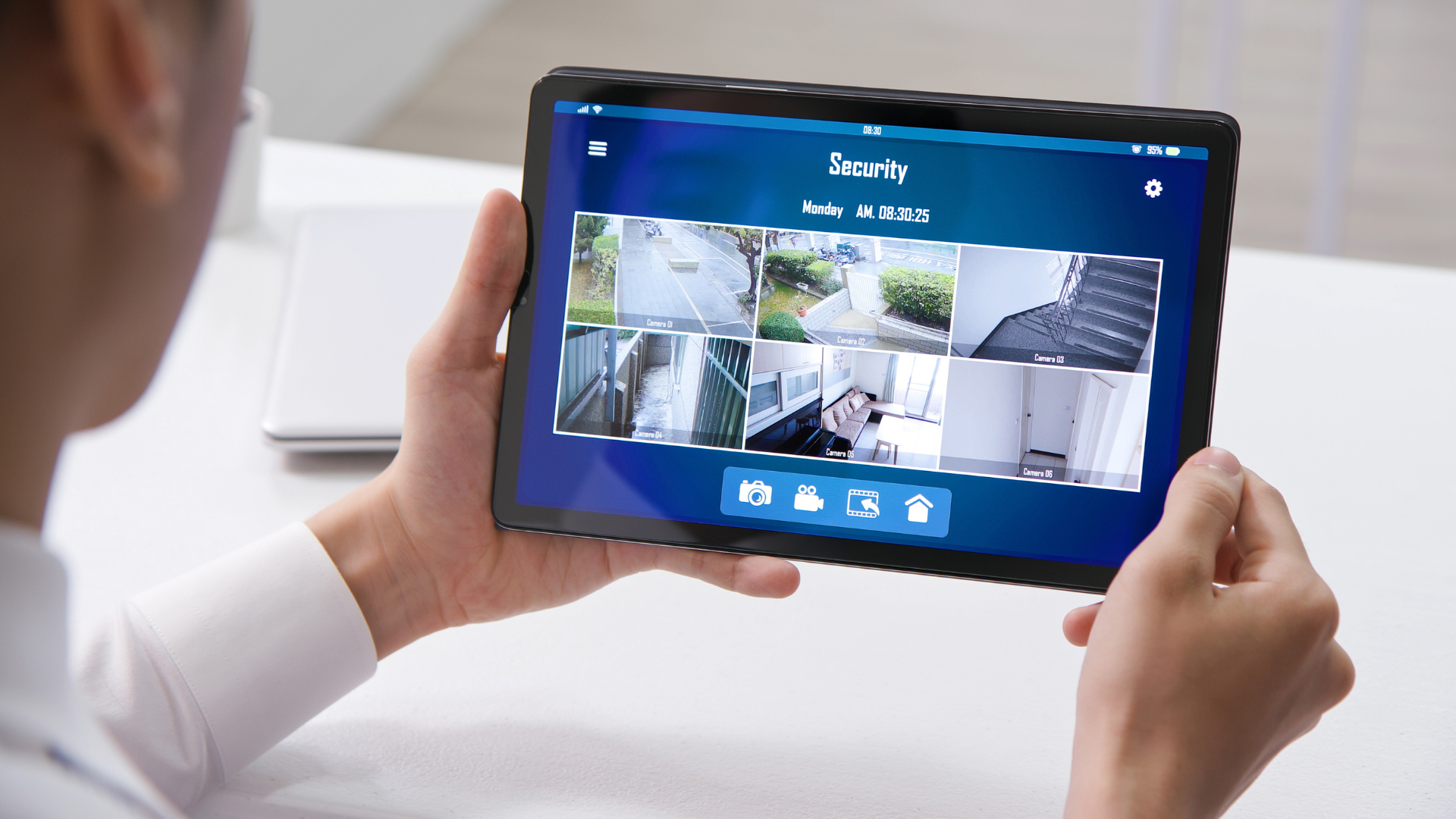 Person holding tablet displaying security camera feeds.