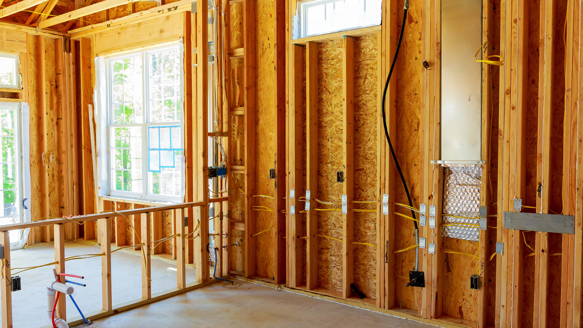 Interior of a house under construction with exposed wooden framing and electrical wiring.