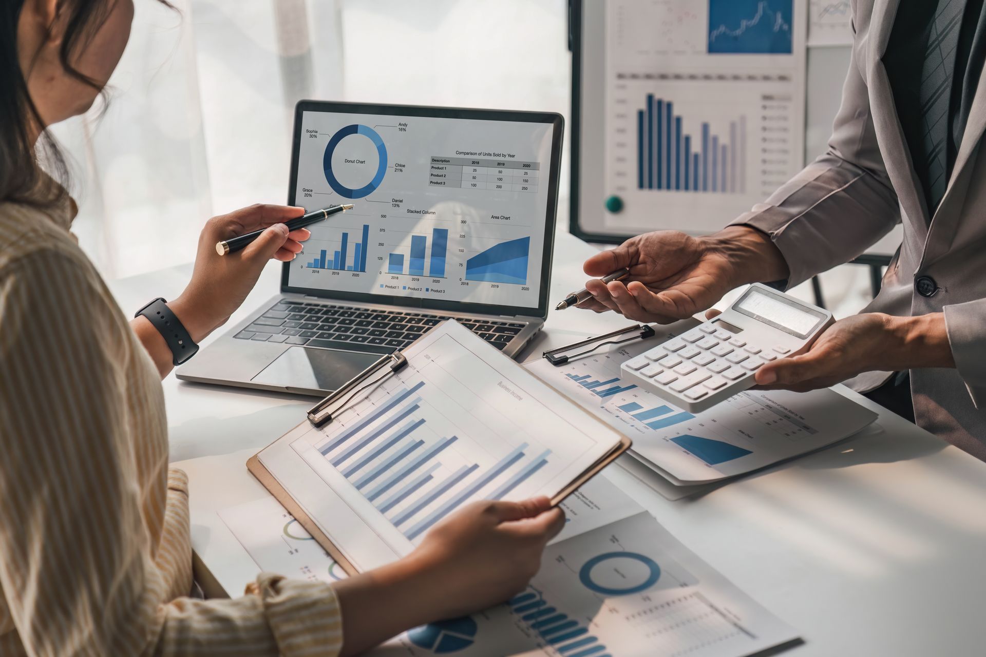 A man and a woman are sitting at a table looking at graphs and charts.