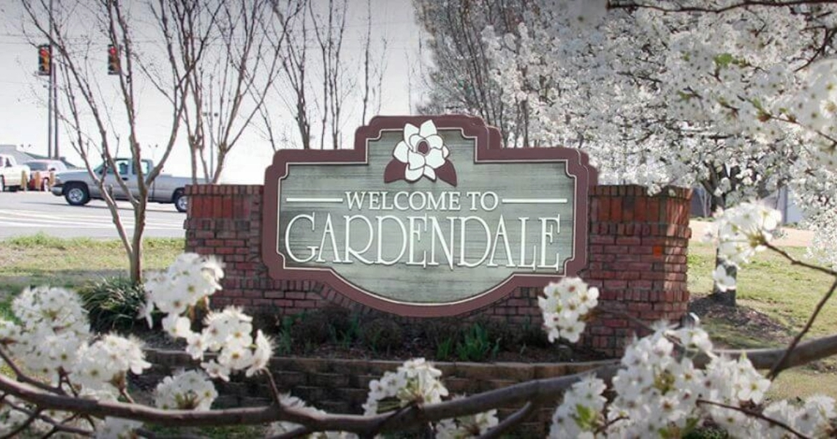 A welcome to gardendale sign is surrounded by white flowers.