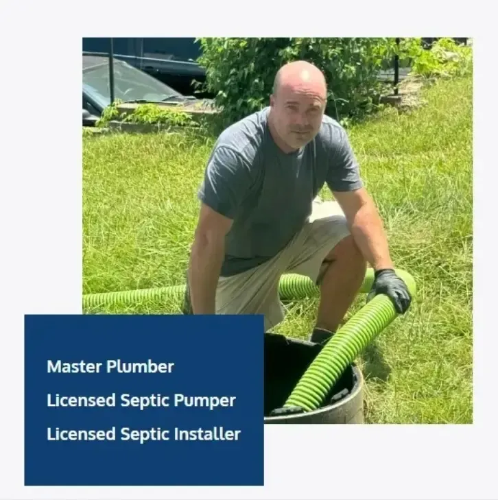 A man is kneeling down in the grass holding a green hose ..