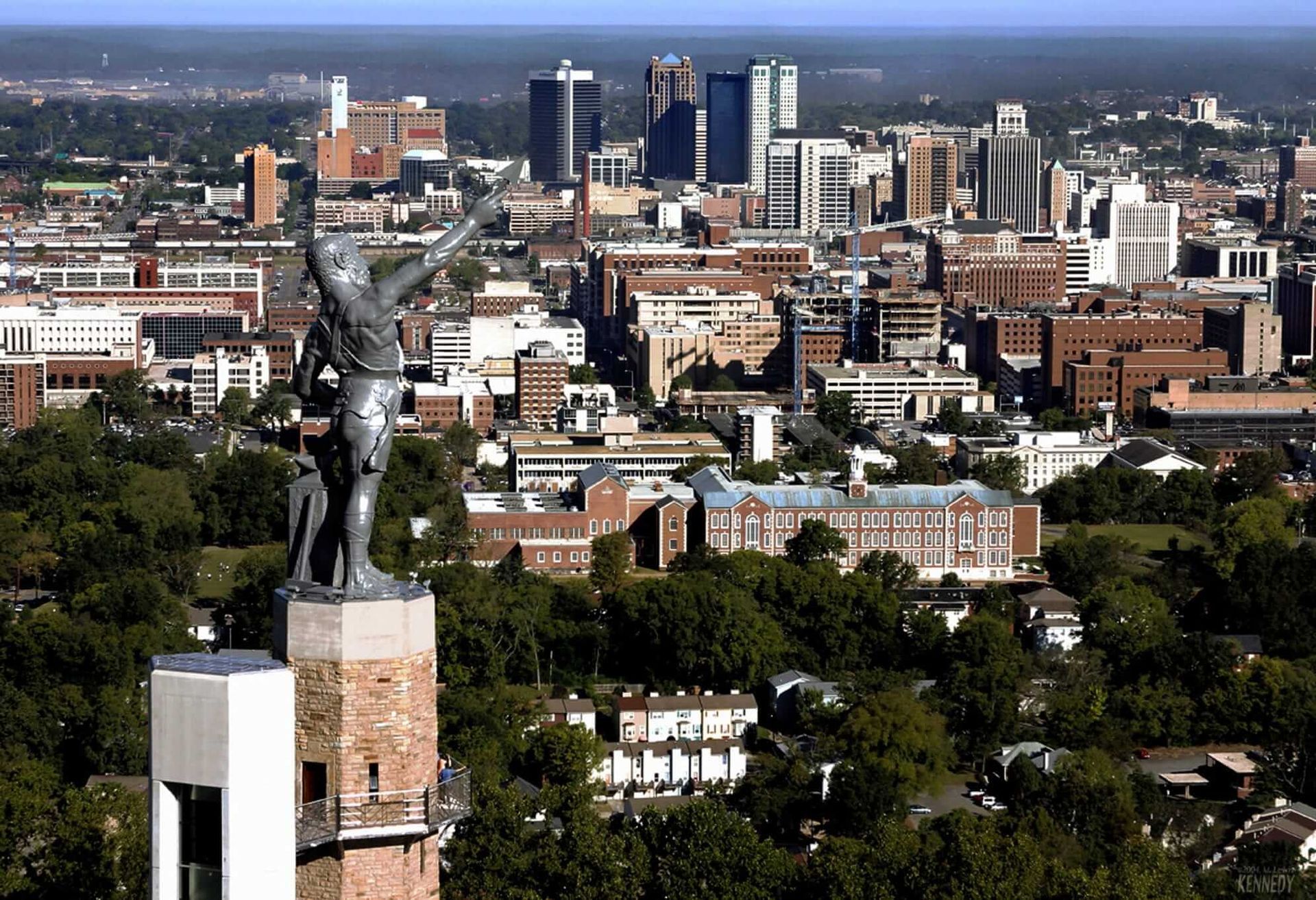An aerial view of a city with a statue in the foreground