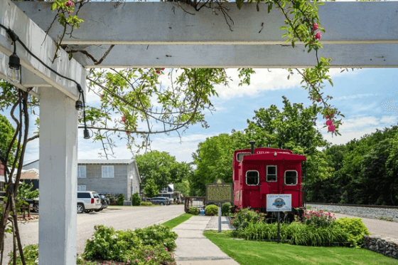 A red train car is parked in front of a white pergola.