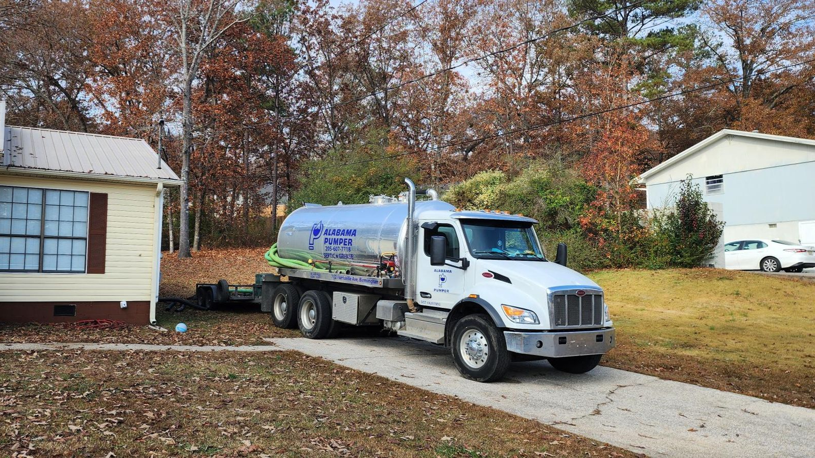 A man in a red hard hat is looking into a manhole cover.