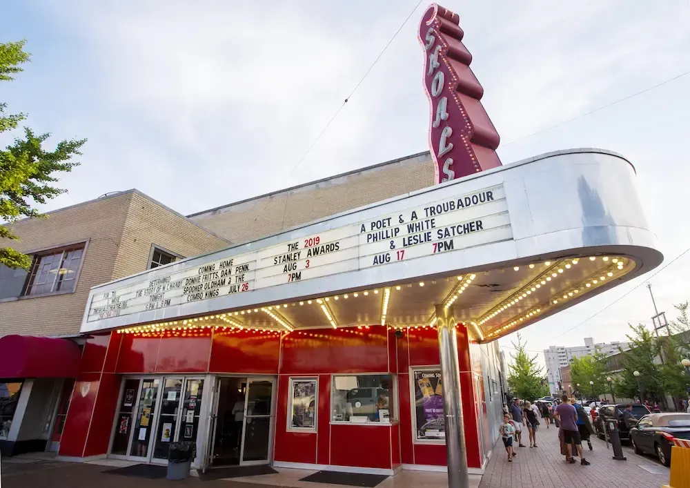 A red train car is parked in front of a white pergola.