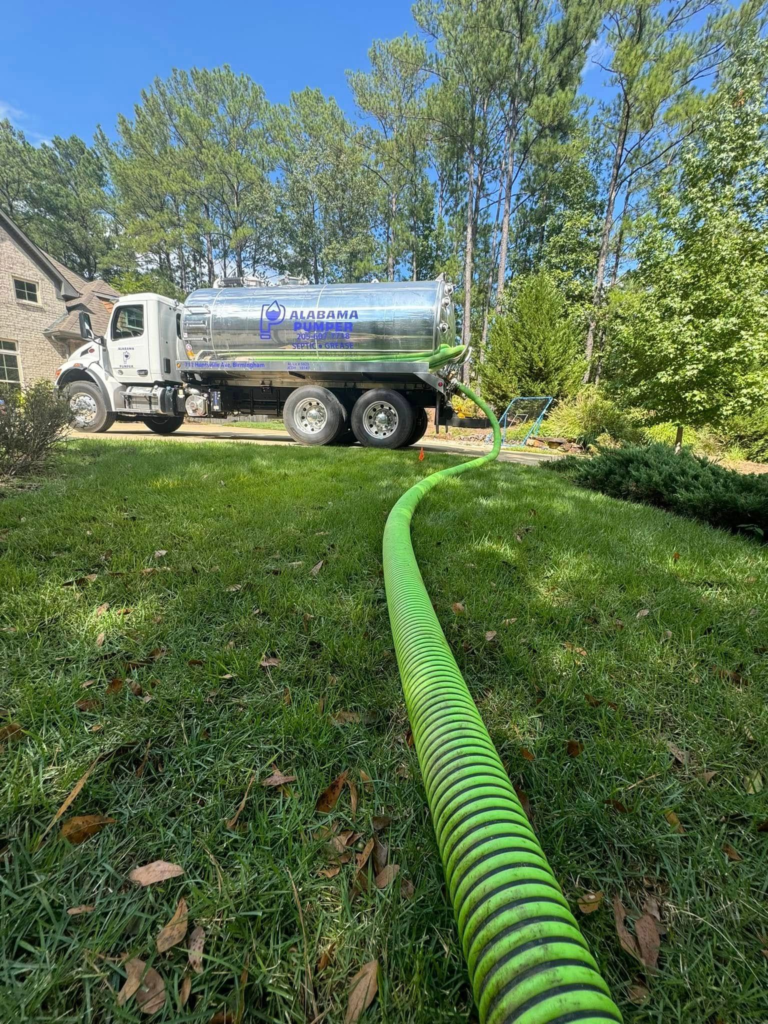 A Alabama Pumper septic tank truck with a green hose attached to it.