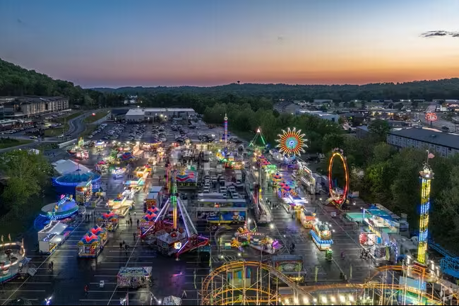 An aerial view of a carnival at night with a roller coaster.
