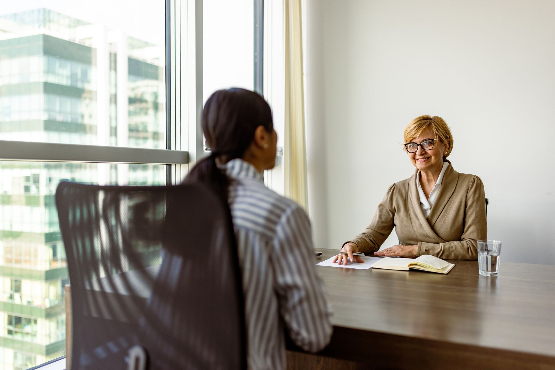 Woman in business attire interviewing a candidate in a modern office setting.