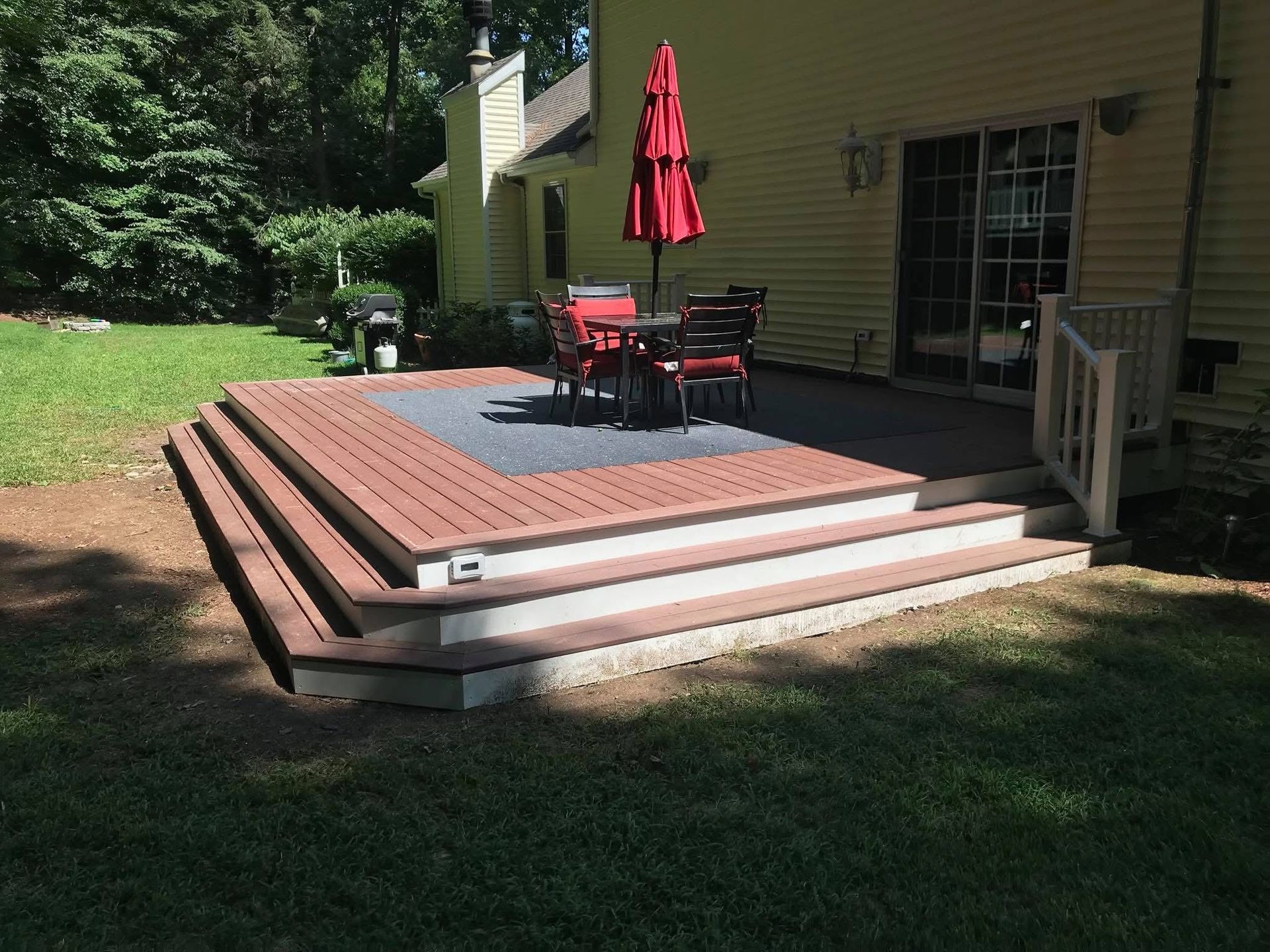 Woman in straw hat smiles, holding wine glass near a lake.