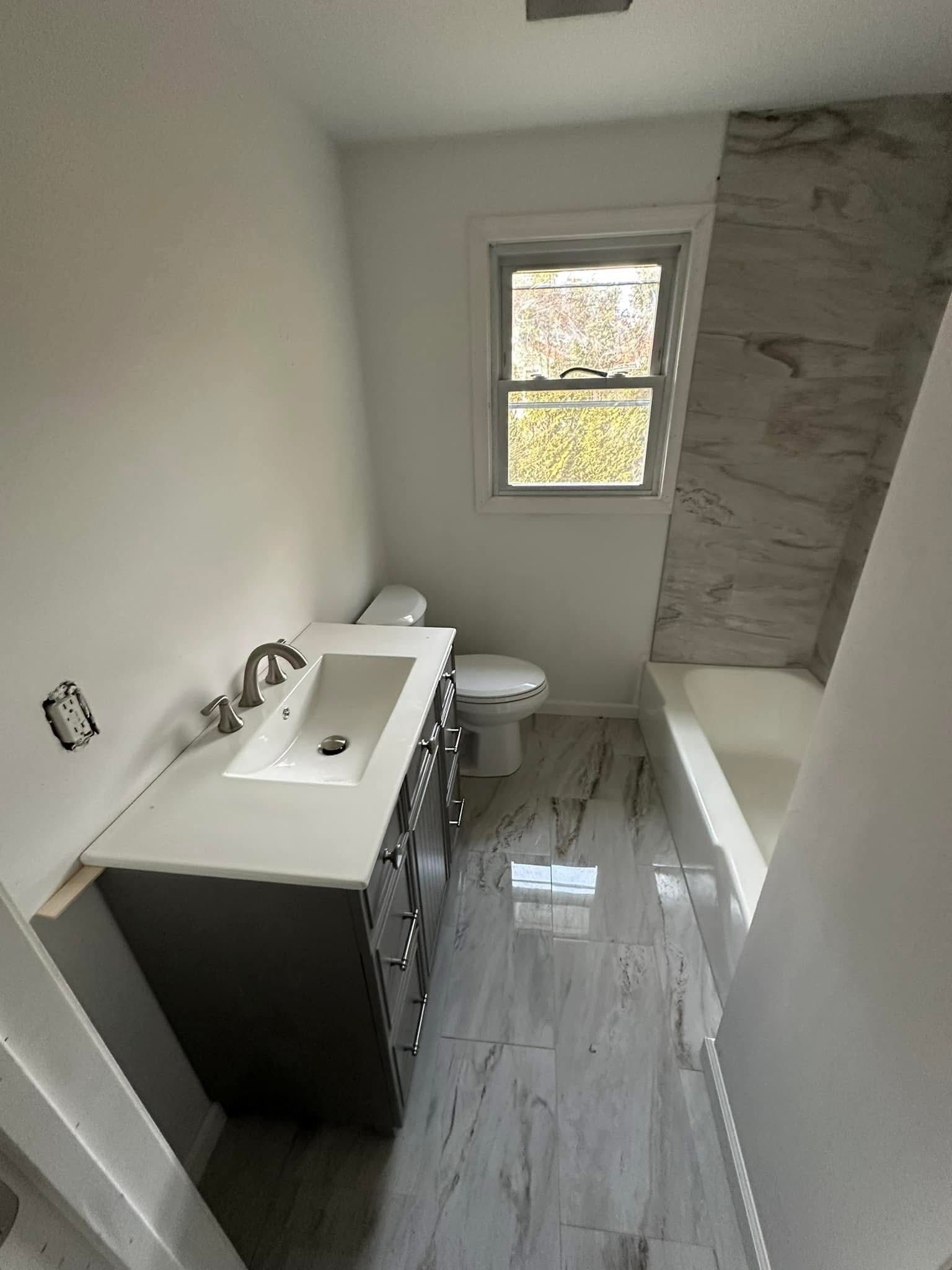 Woman in straw hat smiles, holding wine glass near a lake.