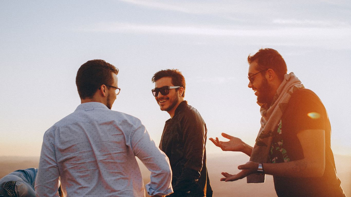 A group of men are standing on top of a hill talking to each other.
