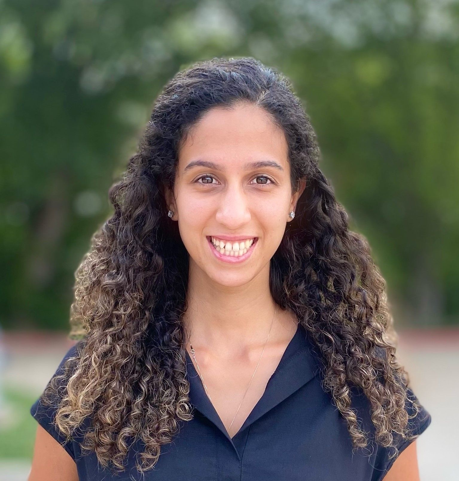 A woman with curly hair is smiling and wearing a black shirt.